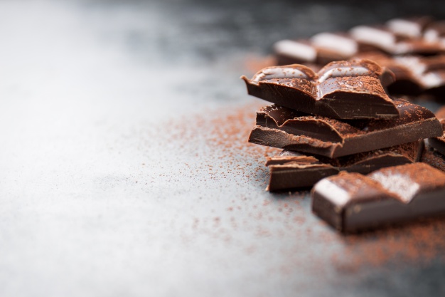 pieces-of-chocolate-on-a-wooden-table-and-cacao-sprinkled_1220-537